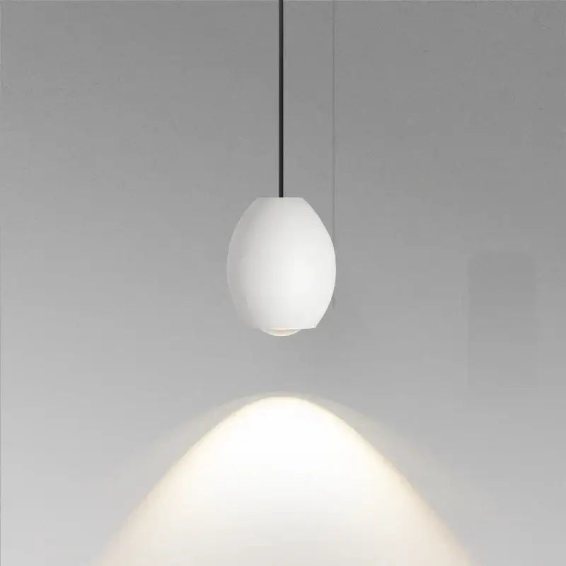 A minimalist white ceramic egg pendant light with matte finish and thin black cord decorbites adjustable pendant light