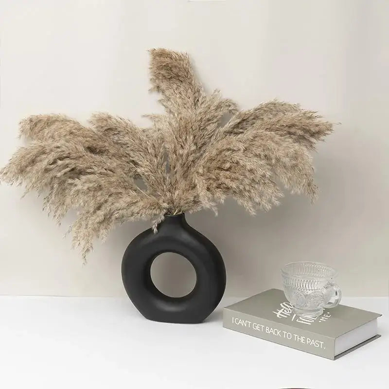 Minimalist black ceramic donut vase with circular cutout and beige pampas grass by decorbites ceramic for living room decor