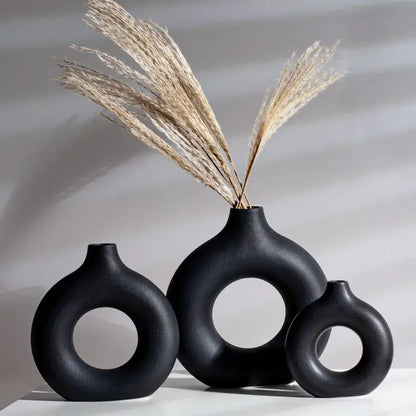 Black decorbites ceramic donut vase set with circular cutouts holding dried pampas grass for minimalist white decor