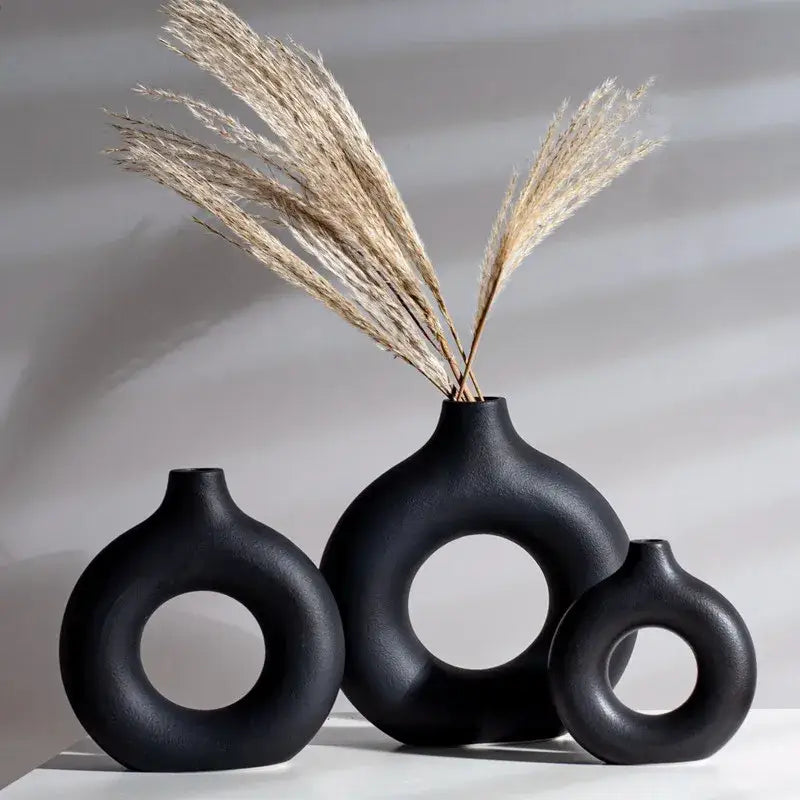 Black decorbites ceramic donut vase set with circular cutouts holding dried pampas grass for minimalist white decor