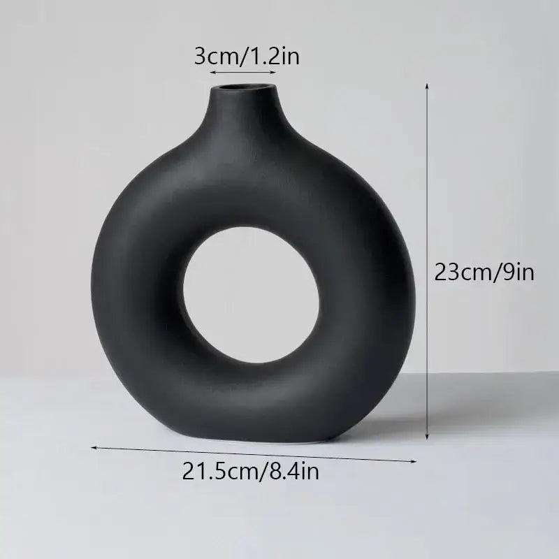 A sleek matte black decorbites ceramic donut vase with modern ring design and smooth rounded contours for minimalist decor