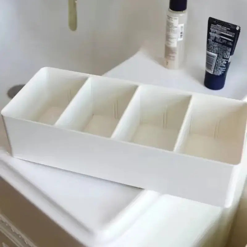 White minimalist rectangular divided storage box with four compartments made of smooth plastic for kitchen tableware