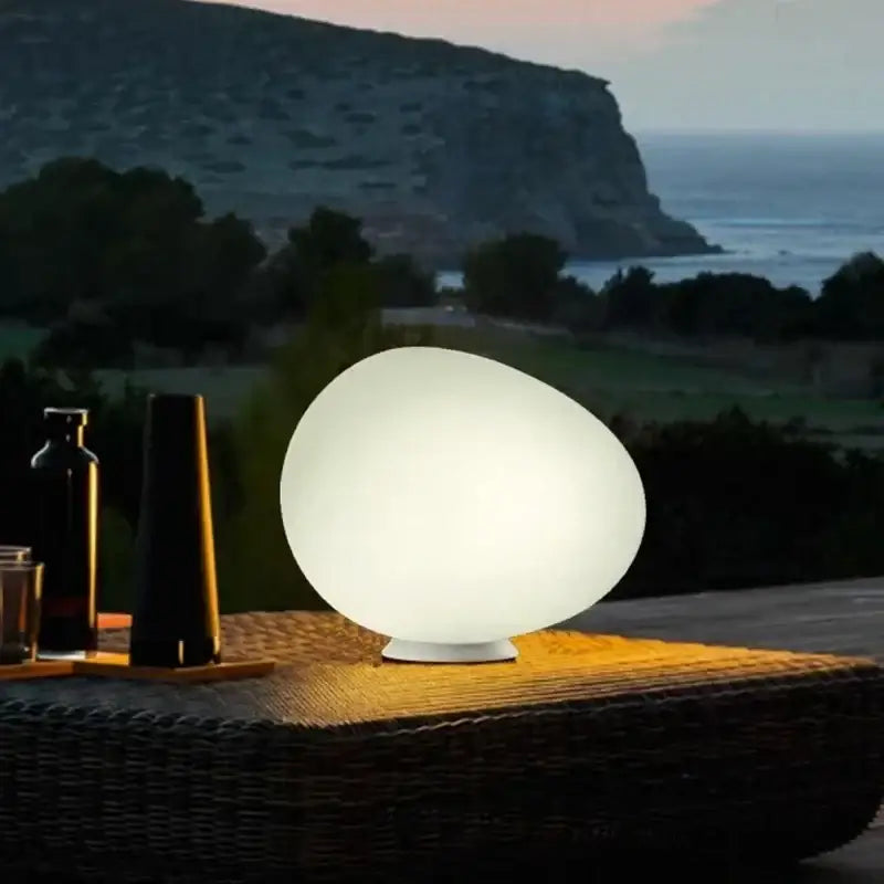 Minimalist white egg glass floor lamp with smooth translucent surface and soft glow for living room use