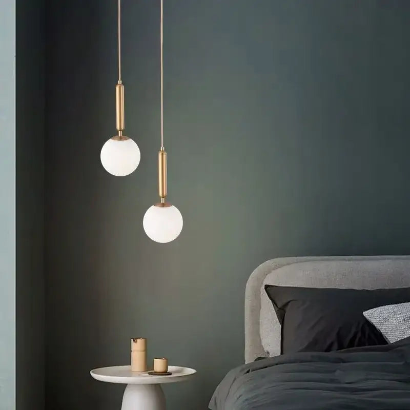 Two minimalist white glass ball pendant lights with brass rods hang from the ceiling for dining room decorbites decor