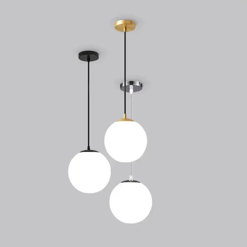 Three minimalist white glass ball pendant lights with frosted shades and metal fixtures in black gold and chrome finishes