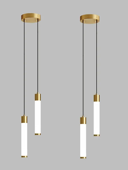Gold-finished cylindrical pendant light with frosted glass tubes and black cords for minimalist kitchen island lighting