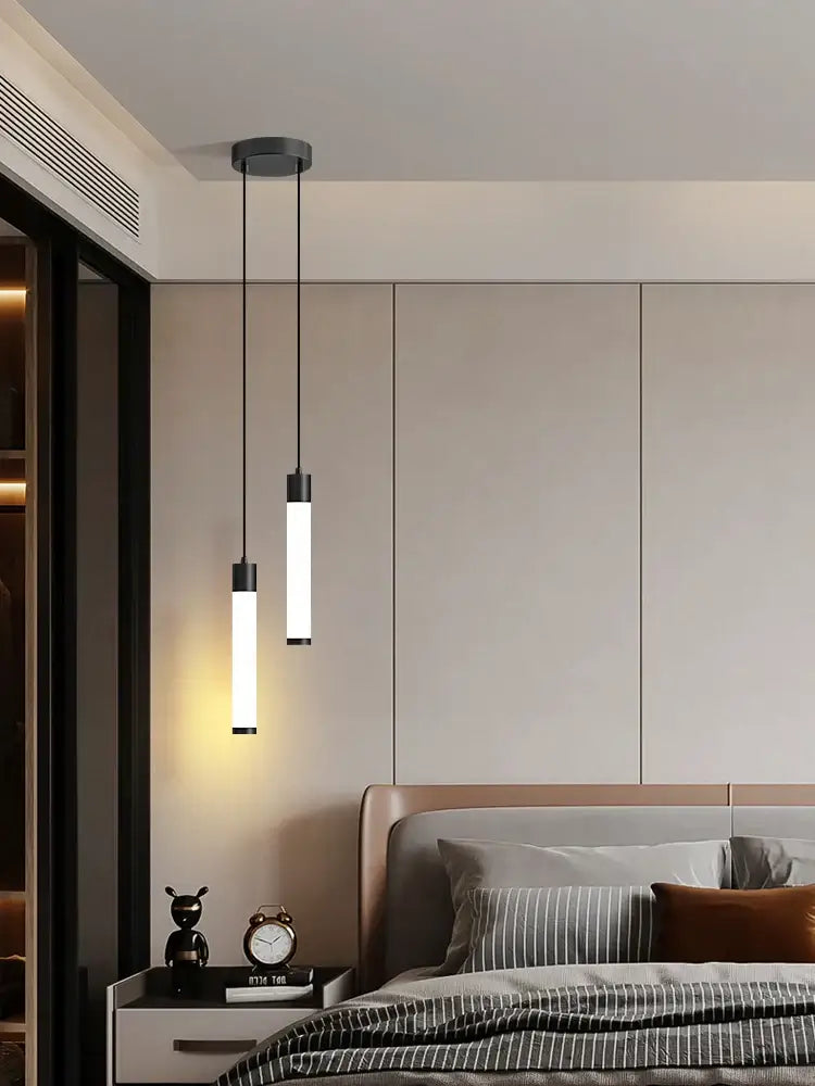 Two sleek cylindrical pendant lights with black fixtures and frosted glass shades complement a minimalist white finish linear pendant light for kitchen island lighting