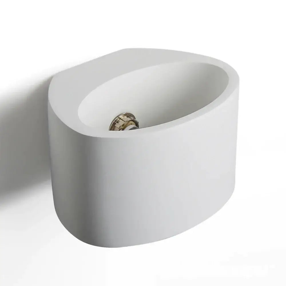 Modern white ceramic wall-mounted bidet with metallic faucet displayed alongside minimalist white and gray gypsum wall lamp