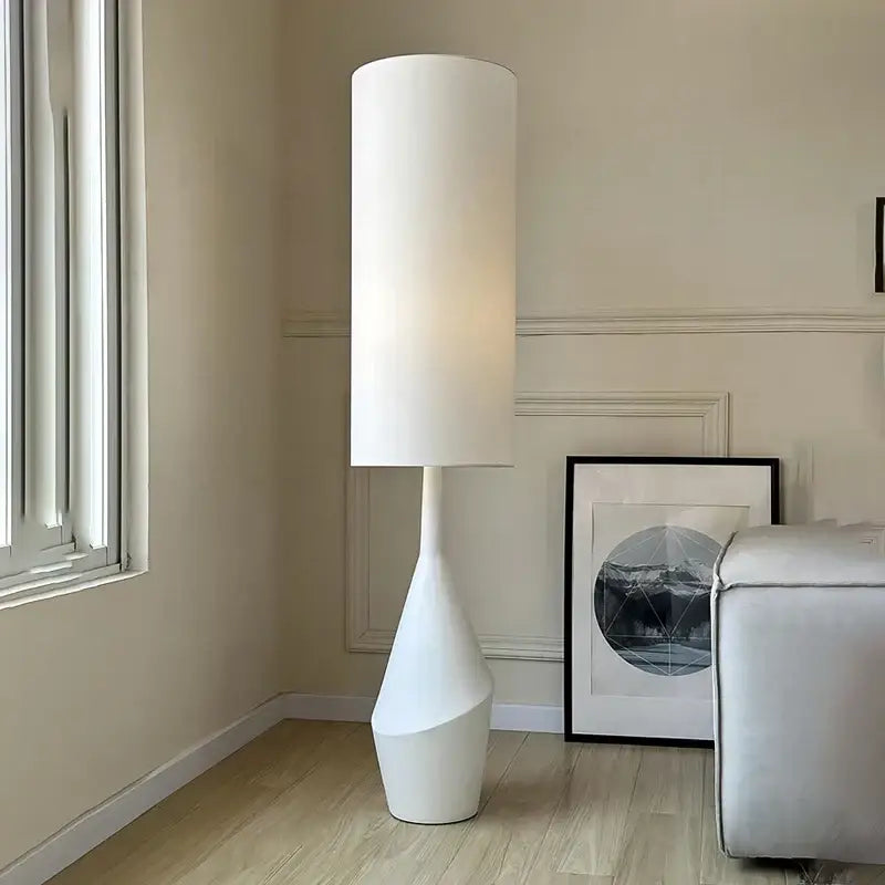 A sleek white led floor lamp with a minimalist cylindrical design and sculpted tapered base for living room use