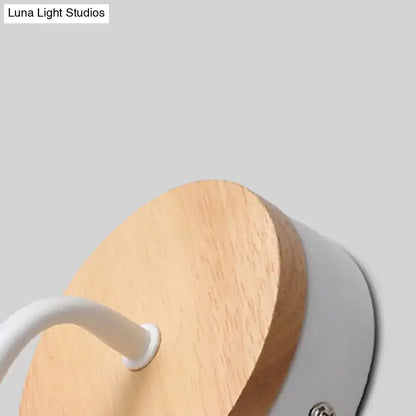Minimalist white metal and wood bare bulb wall sconce with circular wooden base and sleek housing for bedroom lighting