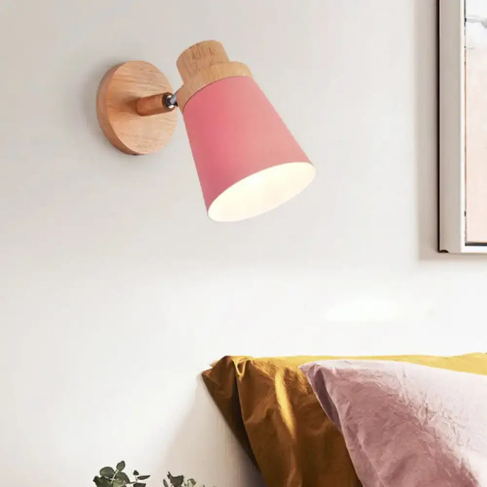 Minimalist wall lamp sconce featuring a pink conical barrel shade with a natural wood base and arm for living room use