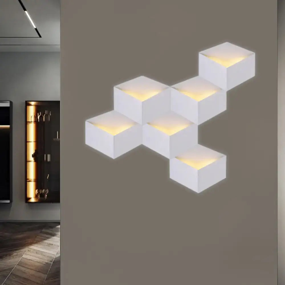 Minimalist white metallic geometric wall lamp with warm glowing light from cube-shaped modules for corridor