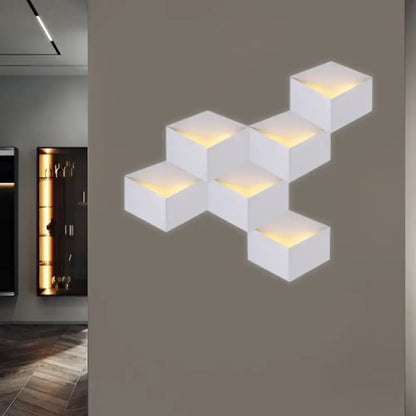 Minimalist white metallic geometric wall lamp with warm glowing light from cube-shaped modules for corridor