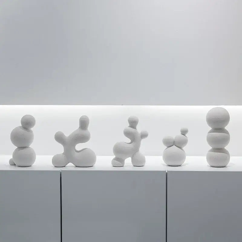 A set of five minimalist white speckled geometric ceramic handicraft sculptures with smooth rounded surfaces for living room decor