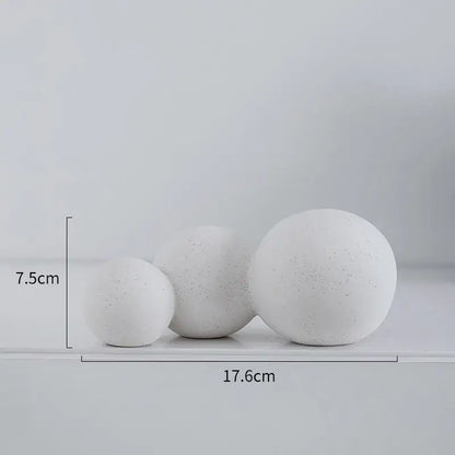 Three white speckled geometric ceramic handicraft spheres of varying sizes displayed on a shelf for living room decor