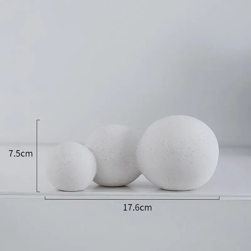 Three white speckled geometric ceramic handicraft spheres of varying sizes displayed on a shelf for living room decor