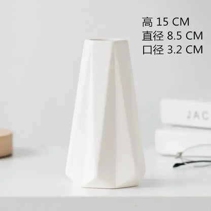 A sleek white decorbites ceramic vase with geometric faceted design and tapered shape for dining room decor