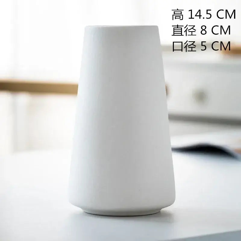 A sleek minimalist white ceramic decorbites ceramic vase with tapered cylindrical shape for dining room decor