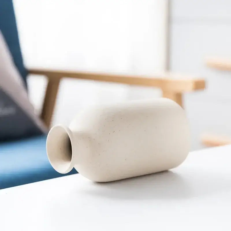 Cream-colored decorbites ceramic vase with smooth matte finish and subtle speckles for minimalist dining room decor