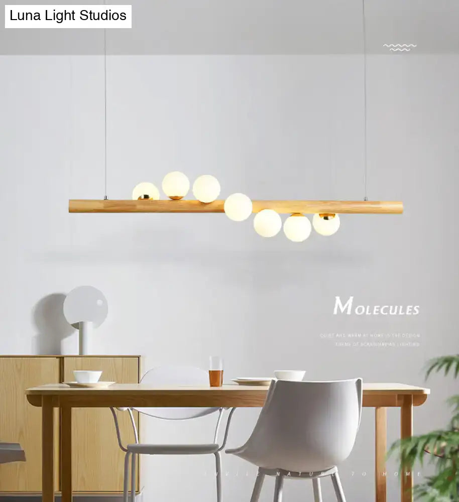 Minimalist wood and glass linear island pendant with slender wooden bar and frosted glass globes for kitchen lighting