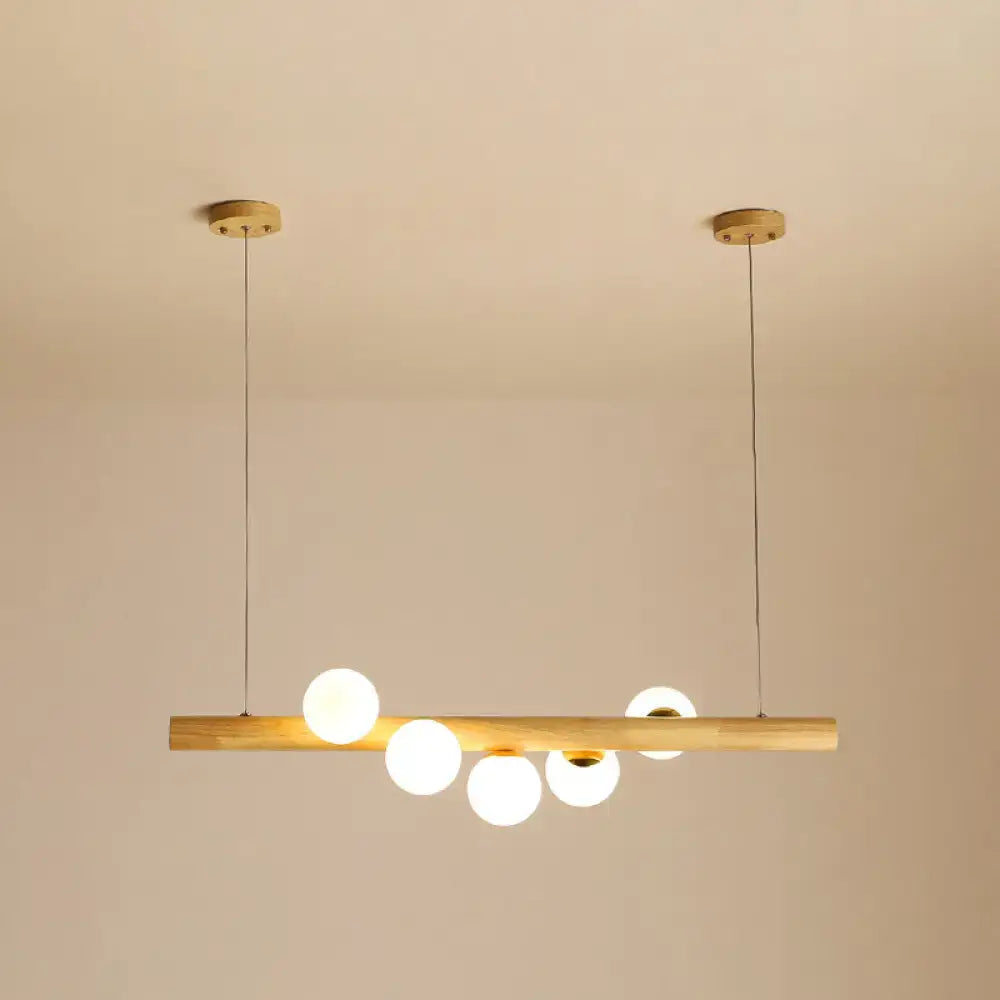 Minimalist wood and glass linear island pendant with natural wood bar and five frosted globe bulbs for kitchen lighting