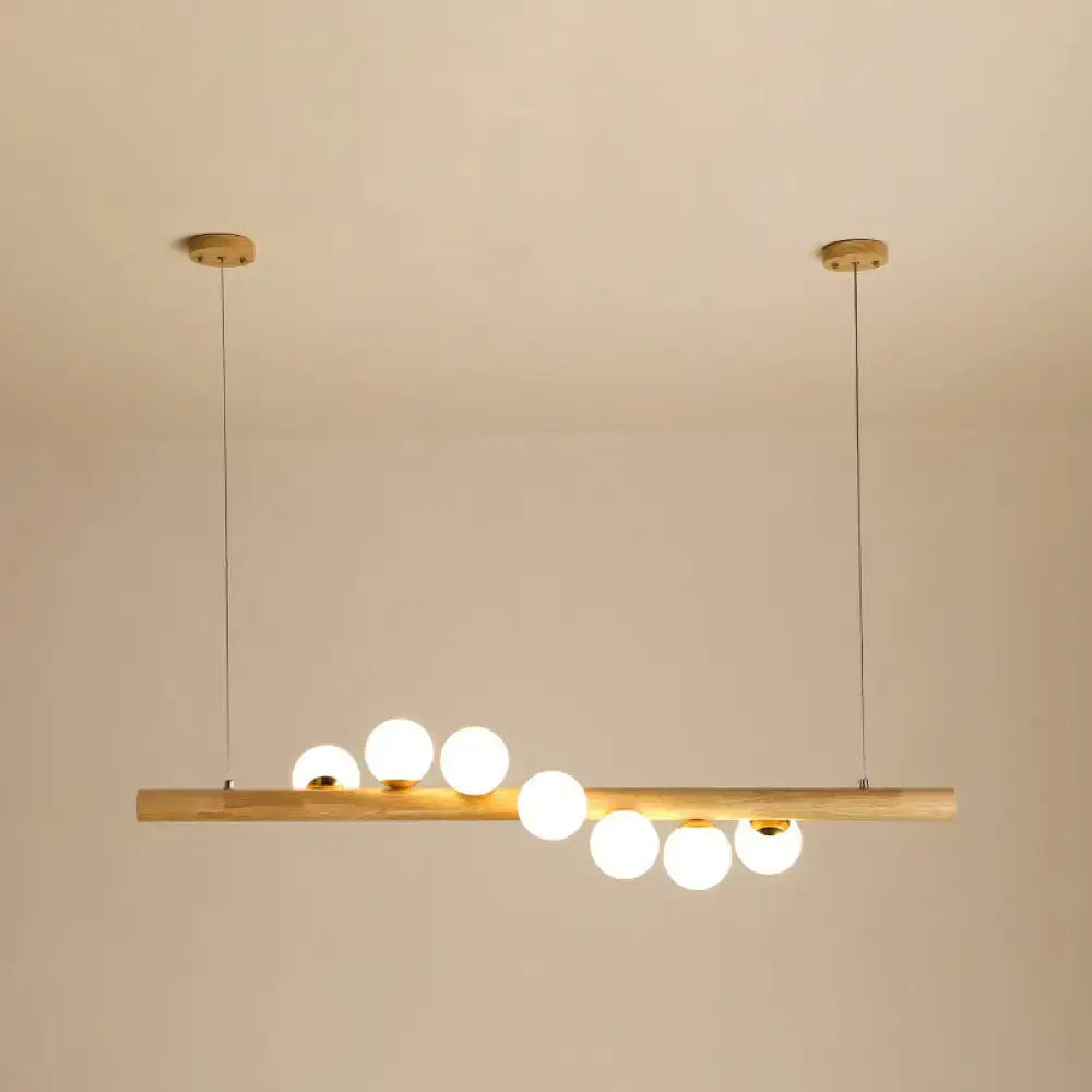 Minimalist wood and glass linear island pendant with six frosted globe bulbs and brass ceiling mounts for kitchen lighting