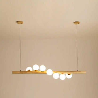 Minimalist wood and glass linear island pendant with six frosted globe bulbs and brass ceiling mounts for kitchen lighting