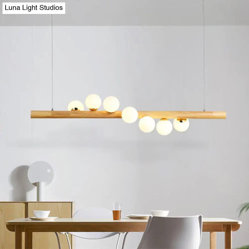 Minimalist linear island pendant with natural wood bar and frosted glass globe bulbs for kitchen lighting