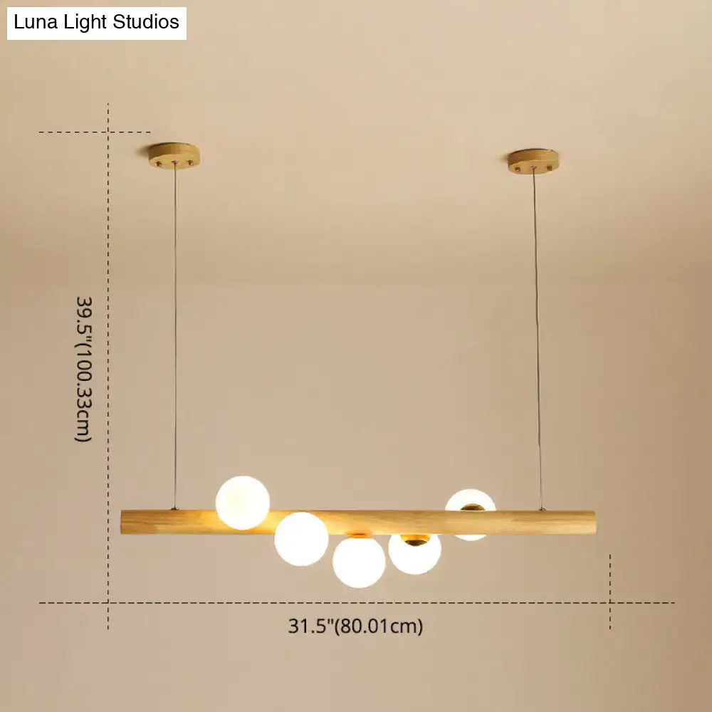 Modern minimalist linear island pendant with natural wood bar and five frosted glass globe bulbs for kitchen lighting