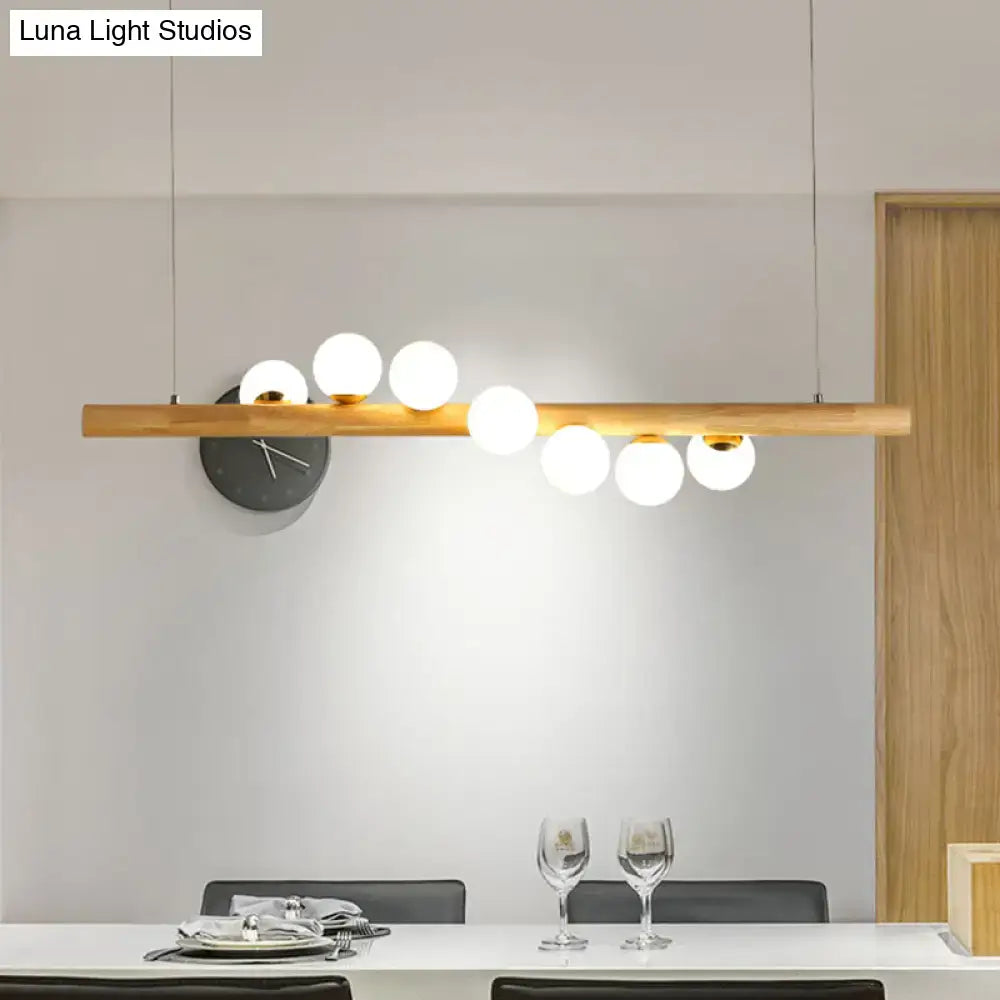 Minimalist wood and glass linear island pendant with white spherical globes and a sleek wooden bar for kitchen lighting