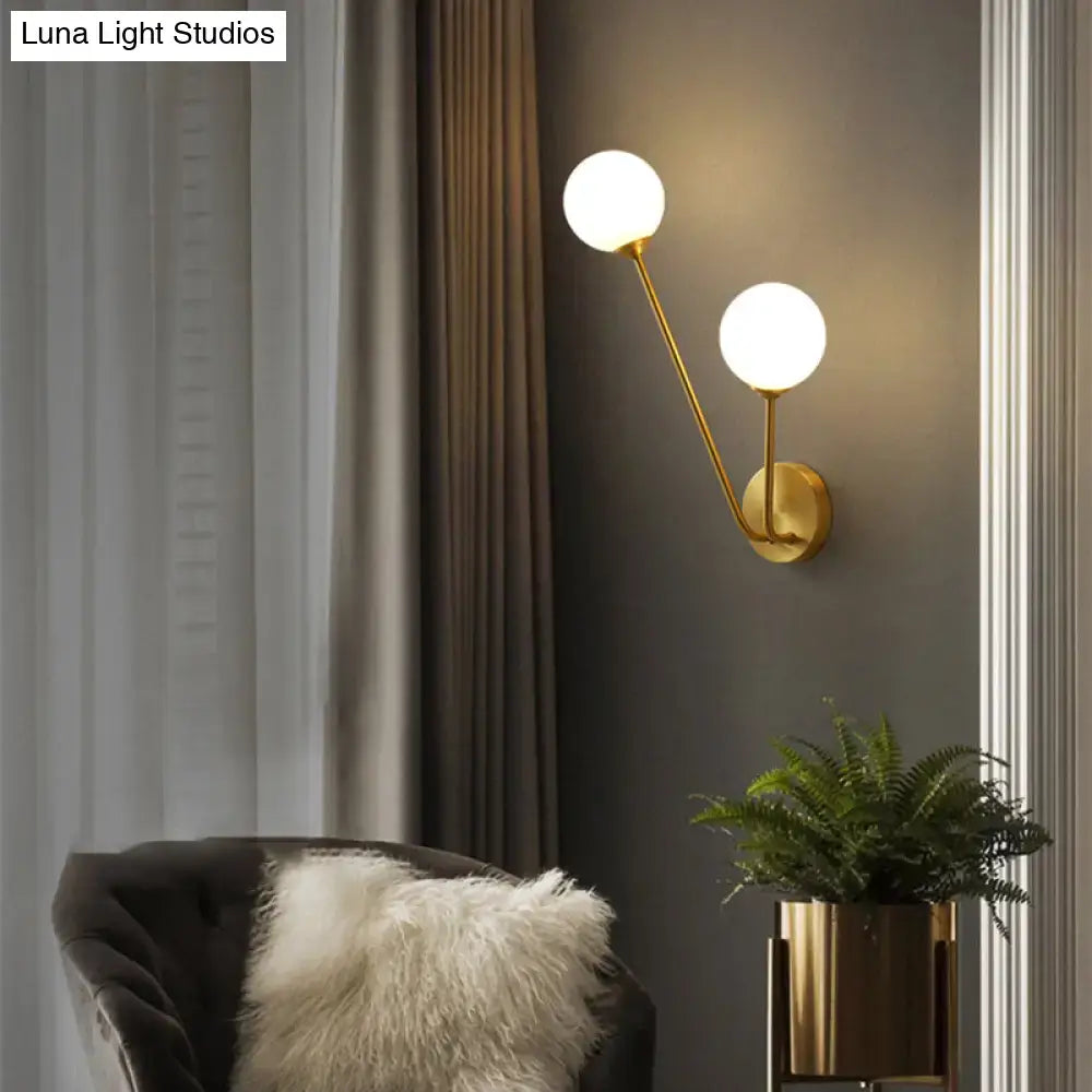 Minimalistic gold-toned brass branch wall lamp with two spherical frosted glass shades for bedroom lighting