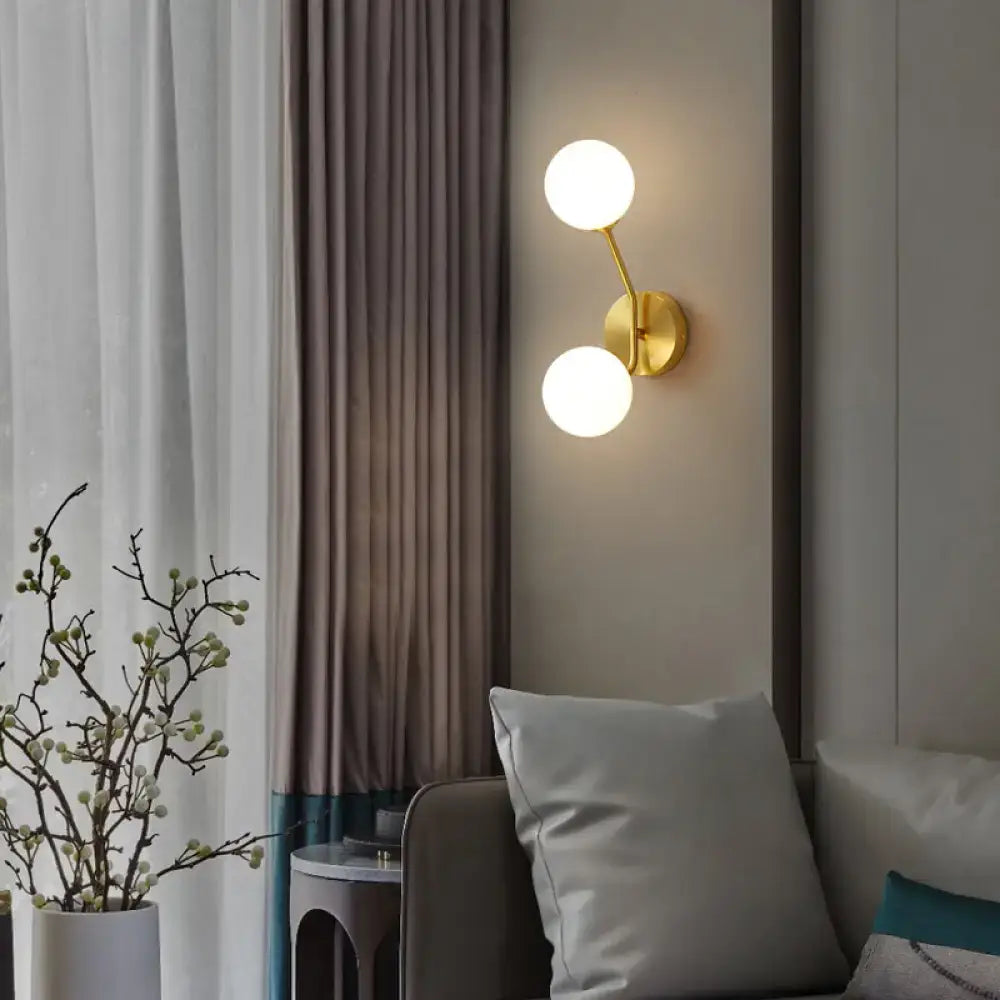 Gold-toned minimalistic brass branch wall light with two frosted glass globes for bedroom wall lamp lighting