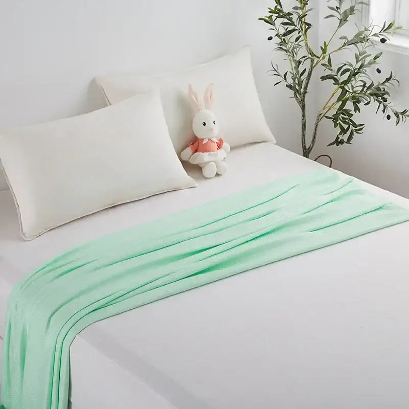 A soft mint green bamboo fiber cooling summer blanket with diamond quilt texture draped elegantly on bed decorbites bamboo fiber