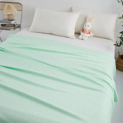 A soft mint green bamboo fiber cooling summer blanket with textured woven fabric and diamond quilt finish by decorbites