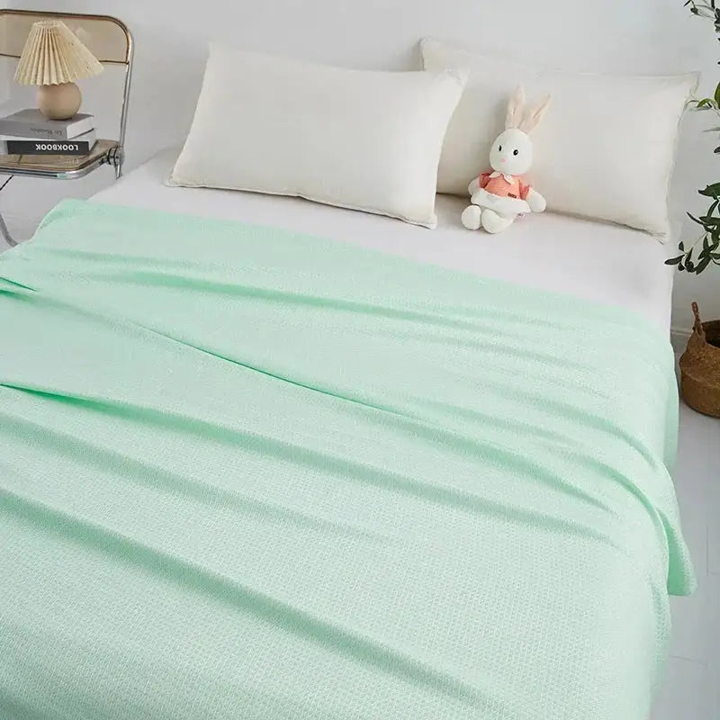 A soft mint green bamboo fiber cooling summer blanket with textured woven fabric and diamond quilt finish by decorbites