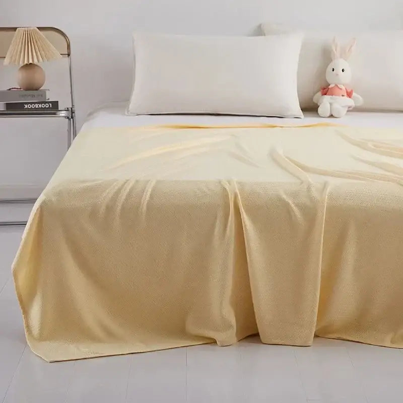 Soft pale yellow textured bedspread over a bed featuring bamboo fiber cooling diamond quilt by decorbites