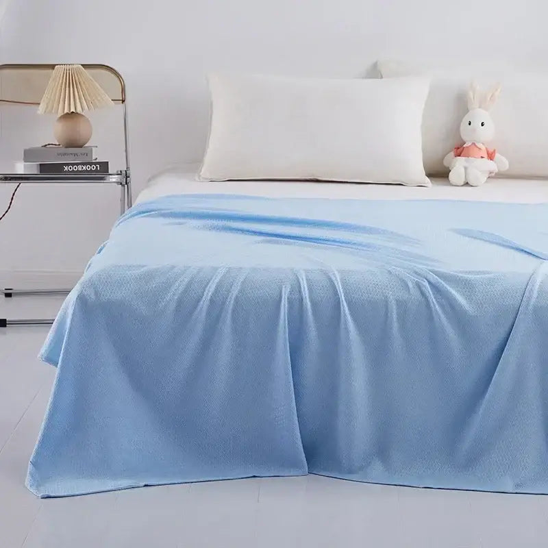 Light blue textured bamboo fiber cooling summer blanket draped over bed for breathable comfort and decorbites bamboo fiber quality
