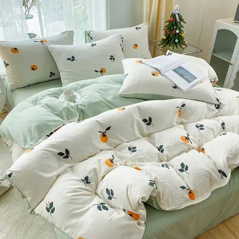White duvet cover with orange fruit and black leaf motifs paired with mint green pillowcases in cartoon heart plant quilt set
