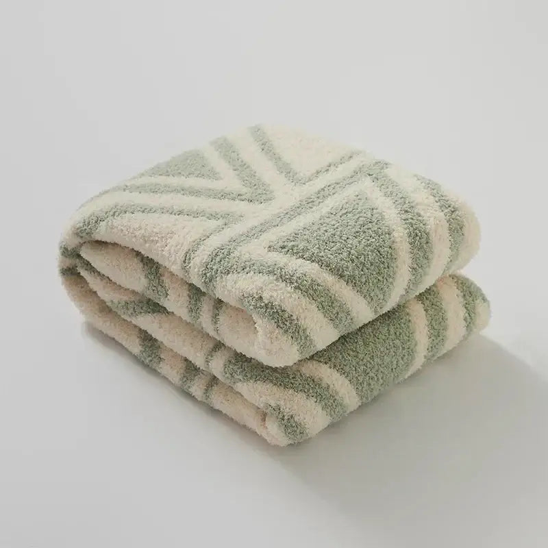 A plush cream and sage green striped decorbites knitted jacquard blanket with soft textured surface for bedroom decor