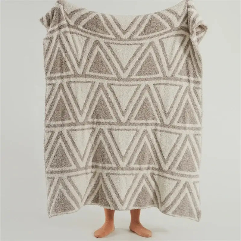 A soft beige and gray textured towel with geometric triangles on a mint green and cream decorbites knitted jacquard blanket