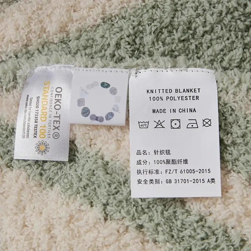 Mint green and cream decorbites knitted jacquard blanket tag showing 100 percent polyester oeko-tex certified label