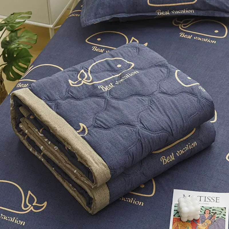 Blue quilted blanket with embroidered whale and best vacation text in gold thread complements mint green daisy print quilt set decorbites daisy print