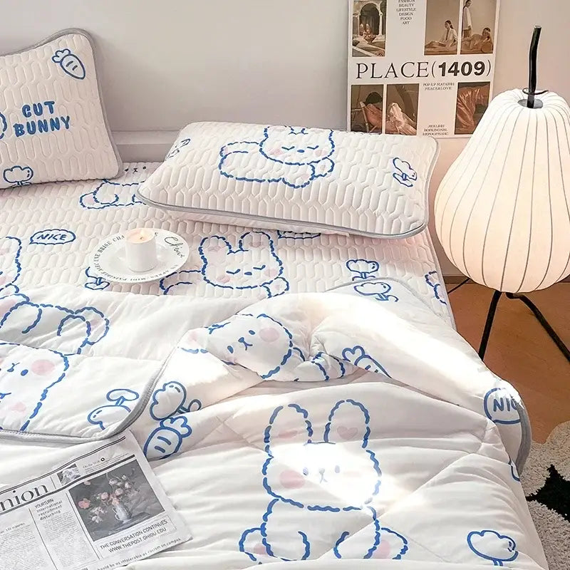 White quilted bed set with blue bunny outlines and pink accents paired with a mint green dinosaur latex fitted sheet set