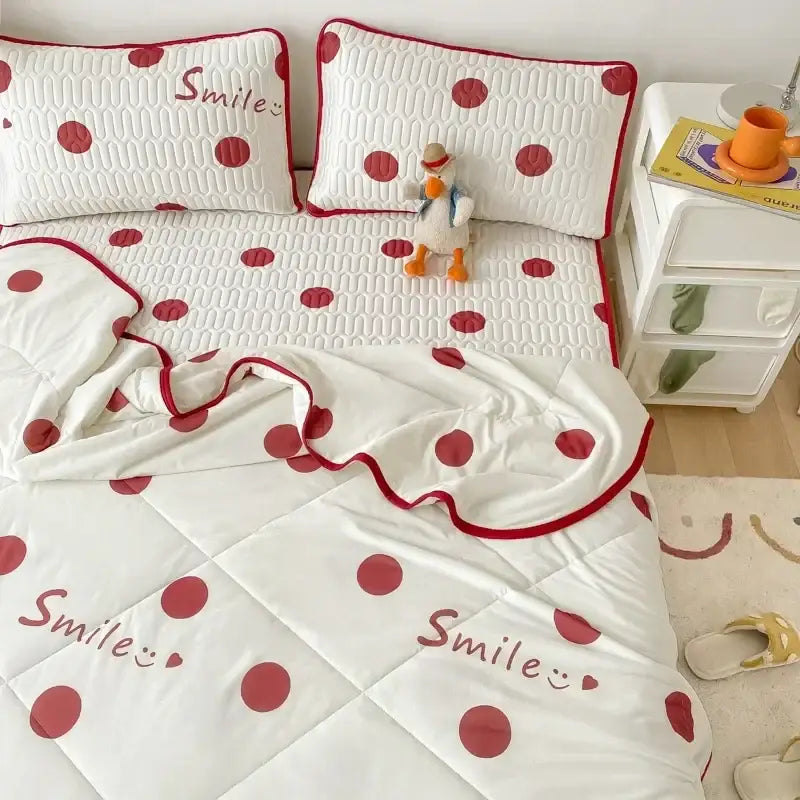 White quilted bed set with red polka dots and smile embroidery paired with mint green dinosaur latex fitted sheet set