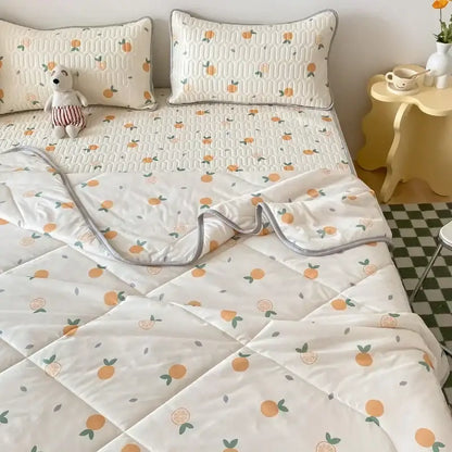 Cream-colored quilted bedspread with orange and green citrus pattern and gray edges paired with latex fitted sheet set