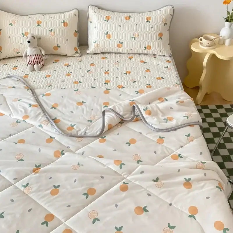 Cream-colored quilted bedspread with orange and green citrus pattern and gray edges paired with latex fitted sheet set