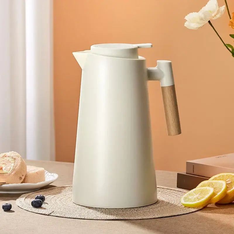 Cream-colored double glazed thermos kettle with wooden handle and white lid for kitchen use and double glazed water storage