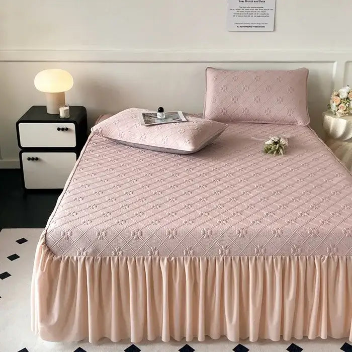 Pink quilted bed skirt set with ruffled hem and matching pillowcases for a mint green floral quilted mattress mat