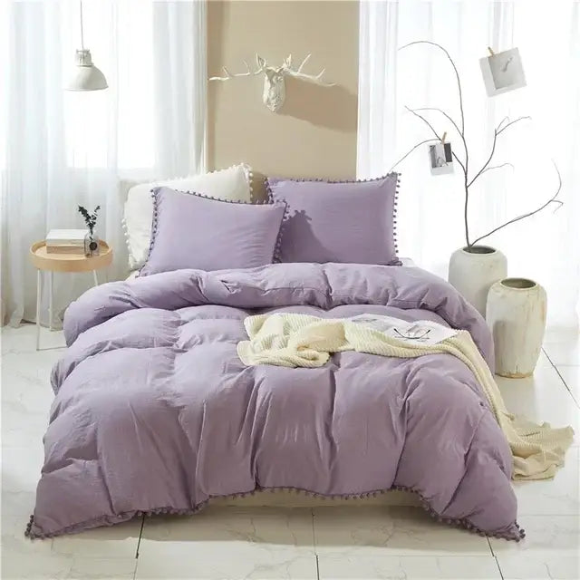 Purple quilted comforter with pom-pom trim featured as part of a duvet cover set for bedroom decor