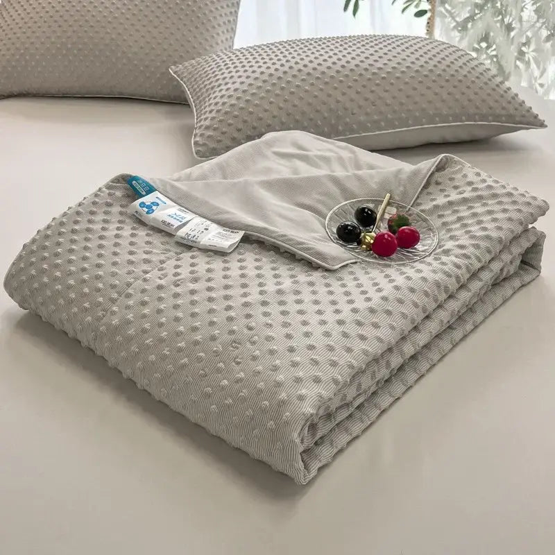 A soft light gray decorbites cooling massage blanket with a quilted textured raised dot pattern for bedroom comfort